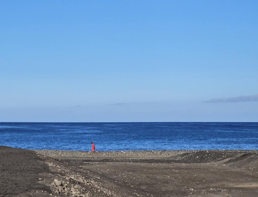 eine Lady in Red am schwarzen Strand